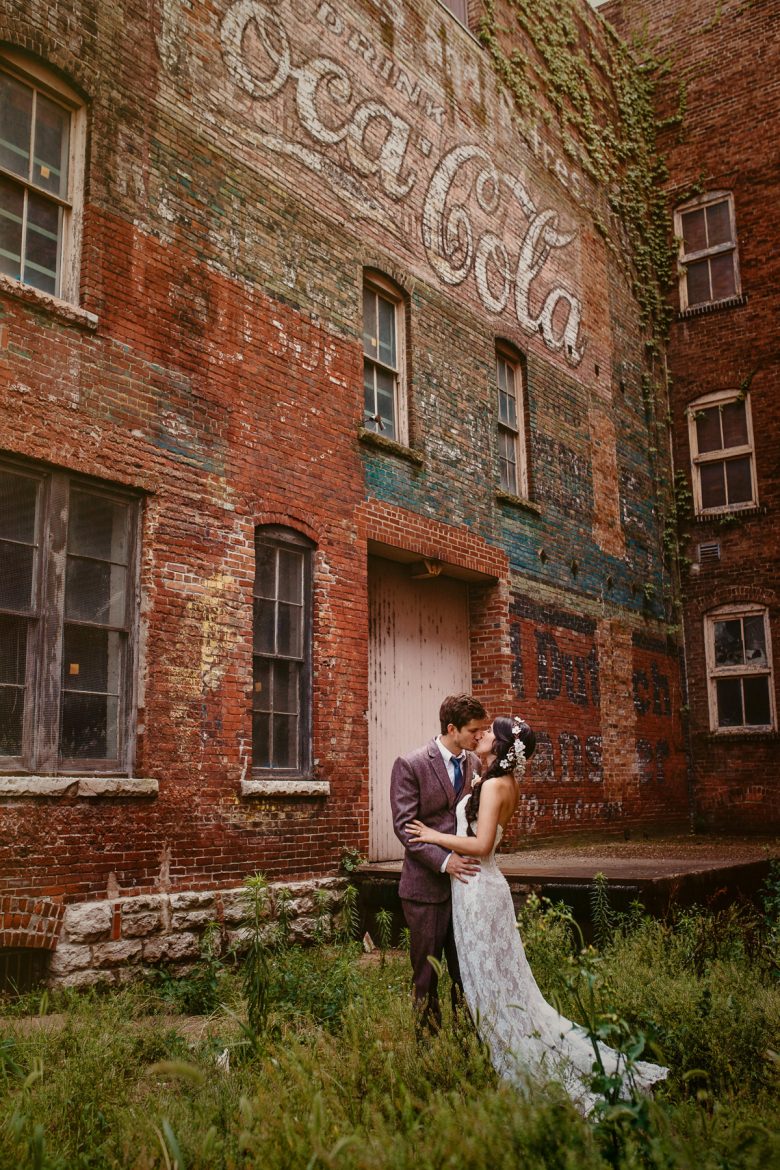 couple standing in front of a brick coca cola sign
