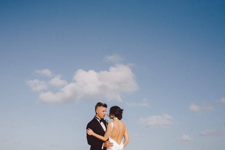 bride and groom in front of sky