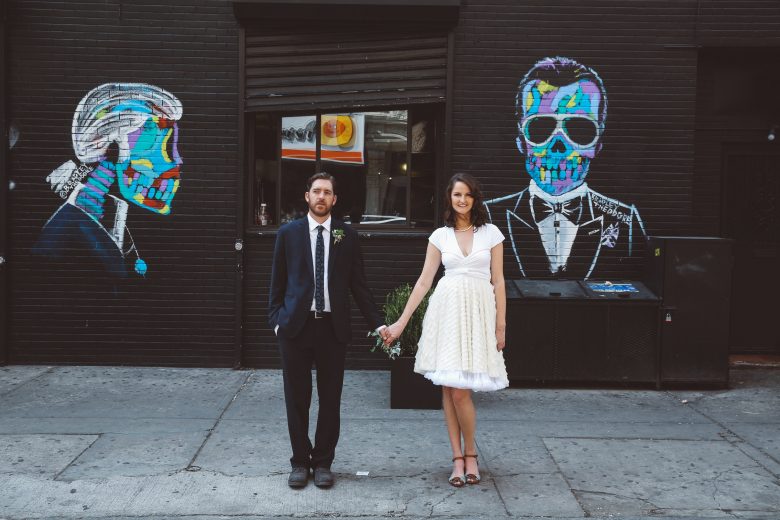 bride and groom in front of skulls on wall