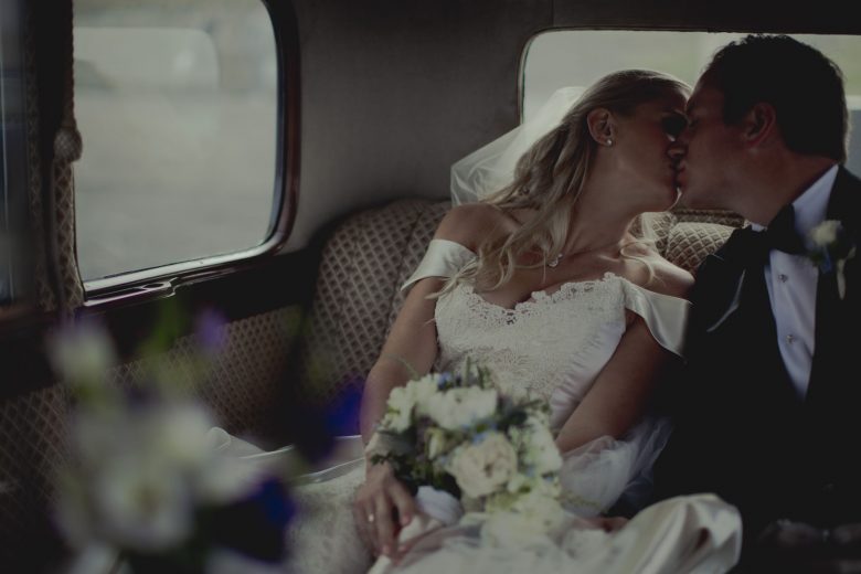 bride and groom kissing in car after wedding