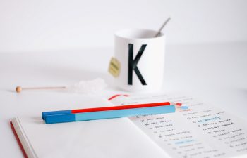 White desk with white K mug and notebook and pencils