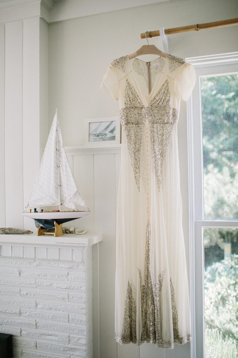wedding dress with sequins hanging by window with toy boat
