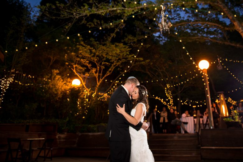 bride and groom dancing under trees and lights