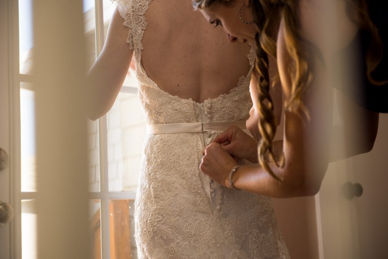 bridesmaid buttoning wedding dress