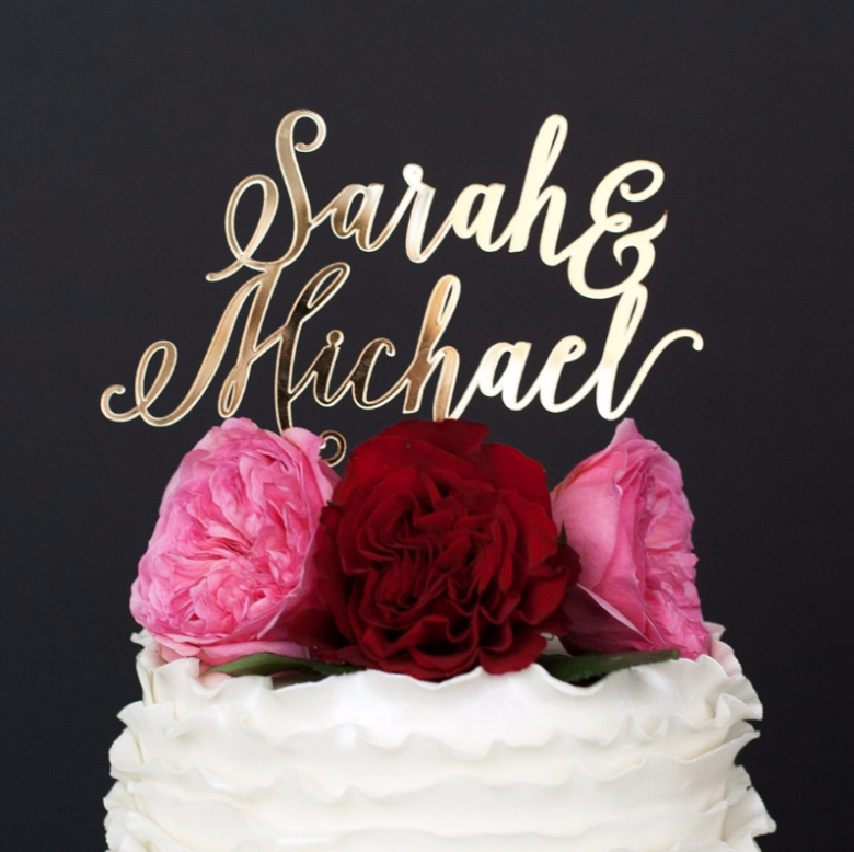 Acrylic cursive cake topper on white cake with red and pink flowers