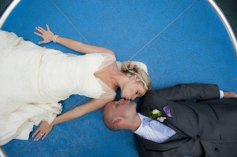 bride and groom kissing while laying down