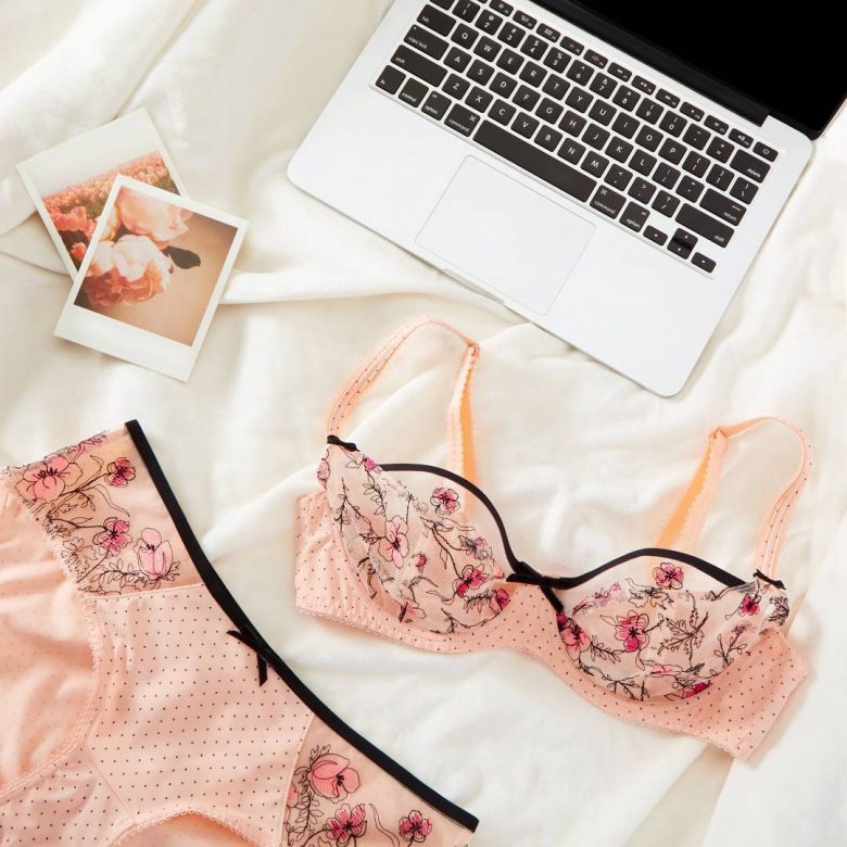 photo of lingerie and laptop on bed