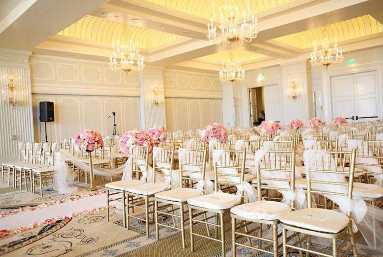 Wedding venue with empty white chairs and pink flowers