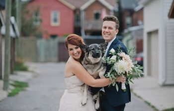 bride and groom holding dog on wedding day