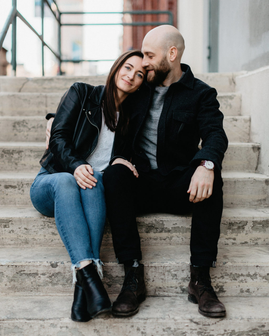 A man and woman sit on steps wearing black, grey, white and denim, enjoying each other's company in a photo by Shaw Photography Co.
