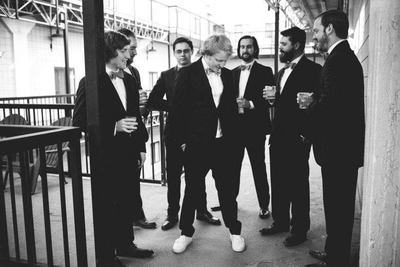 black and white groomsmen surrounding groom