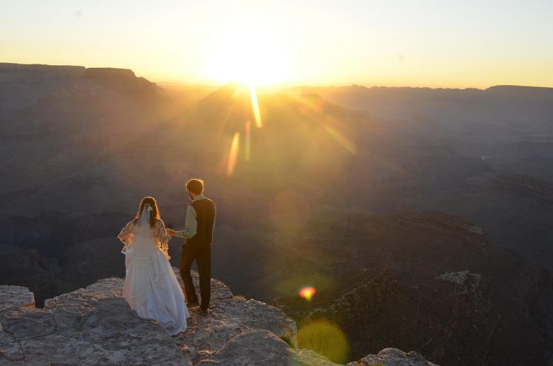 bride and groom on cliff at sunset