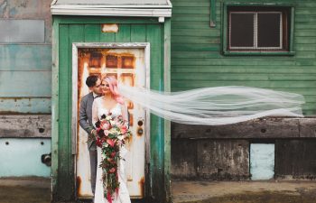 pink-haired bride and groom in front of green building in a photo by Shaw Photography Co.