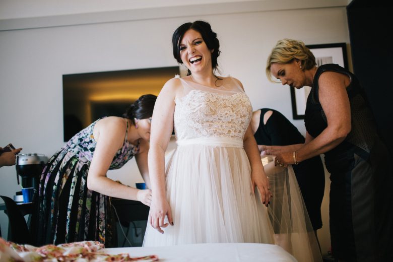 bride getting dressed and smiling