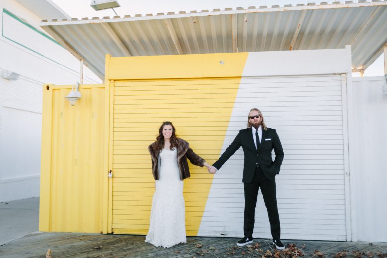 bride and groom in front of white and yellow wall