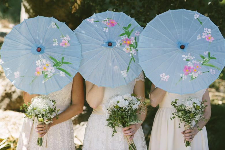 bridesmaids with parasols in front of face