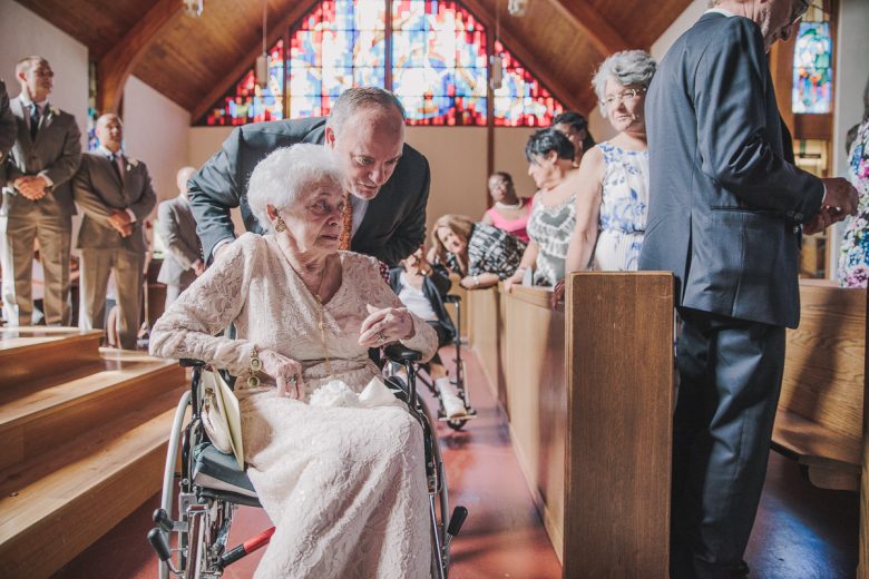 elderly woman in lace dress being pushed in wheelchair in church