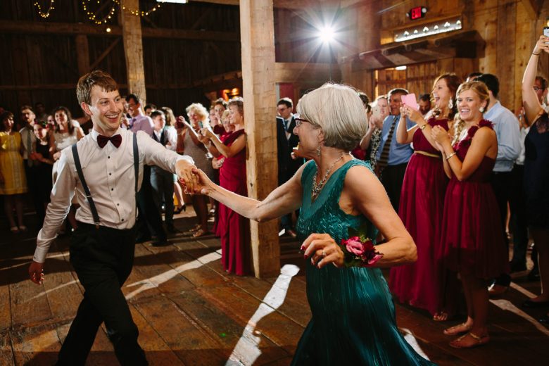 young man and older women dancing in barn wedding
