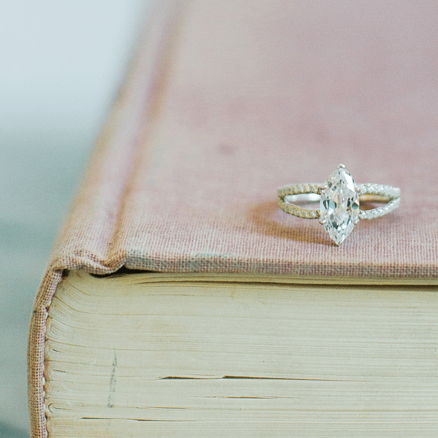 unique antique style engagement ring sitting on a pink book
