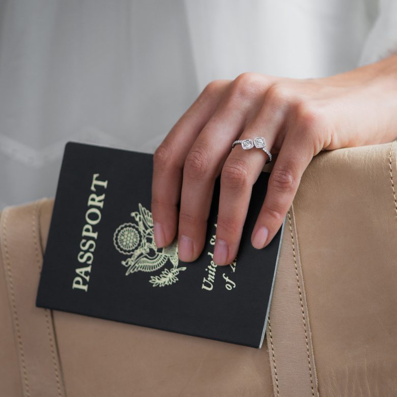 two stone unique diamond engagement ring on the hand of a woman holding a passport