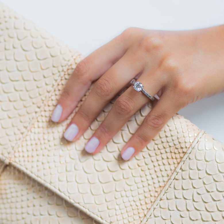 woman holding a purse wearing a simple solitaire engagement ring