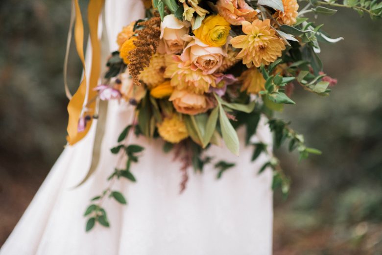 bride holding yellow and orange bouquet
