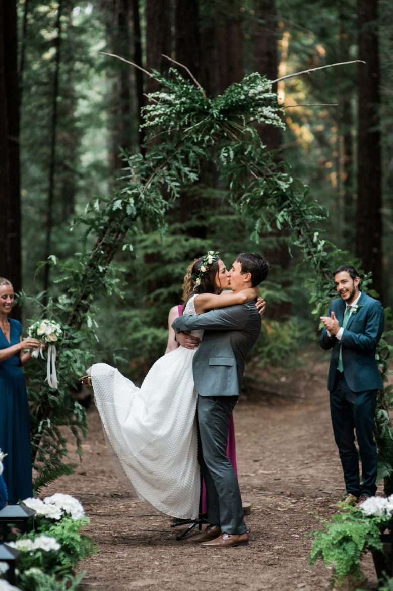 bride and groom kissing during ceremony in forest
