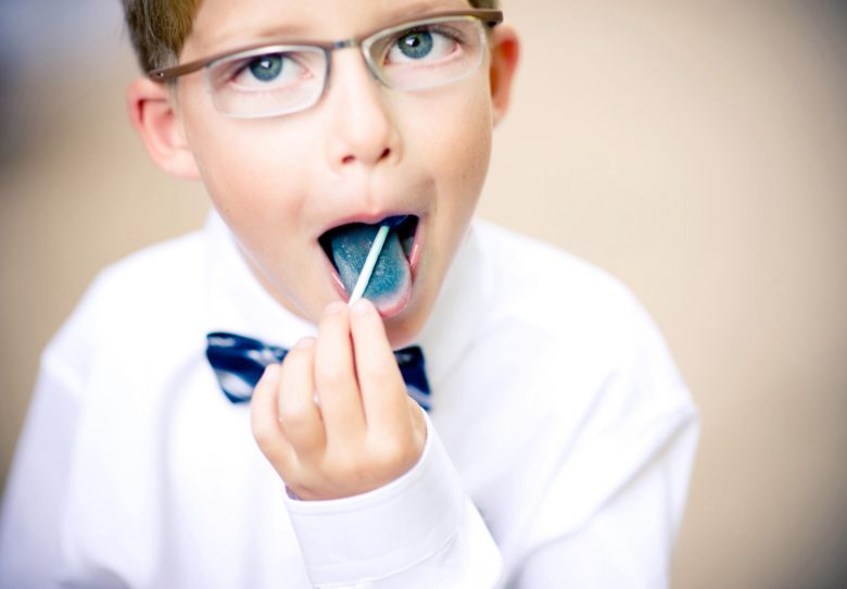 little boy eating a blue lollipop