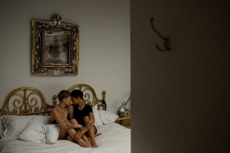tattooed couple sitting together on bed