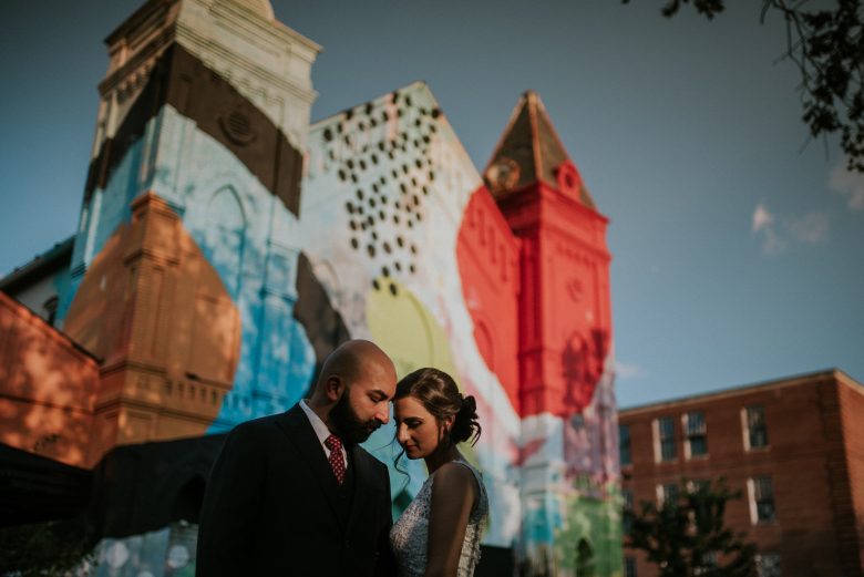 man and woman standing together in front of colorful mural