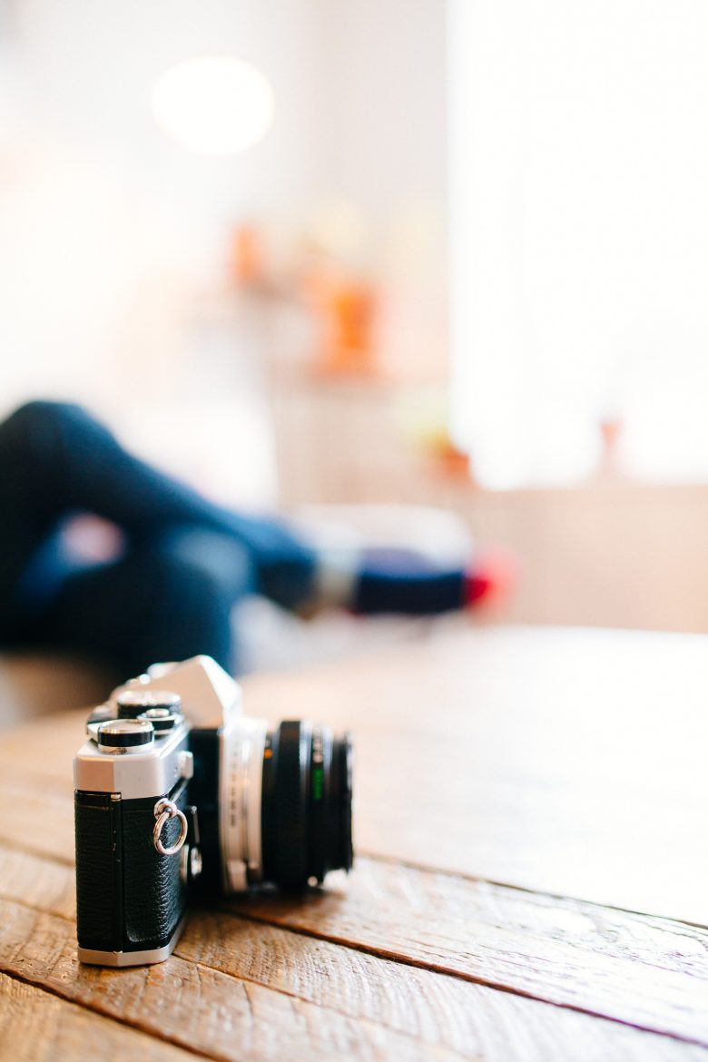 close up shot of a camera with a woman in the background