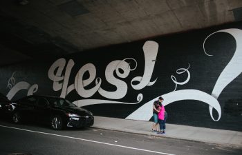 photo of two women in front of yes mural