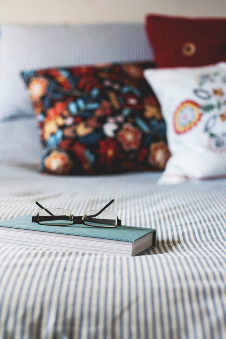 book and glasses on a bed