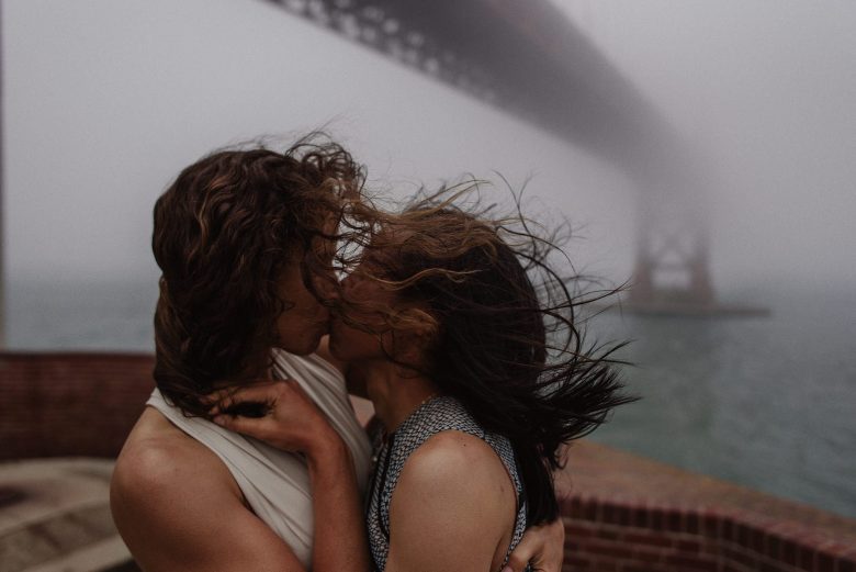 two women kissing under a bridge