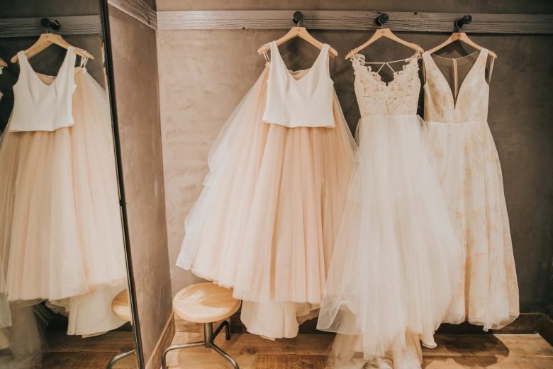 three BHLDN wedding dresses hanging up in a dressing room