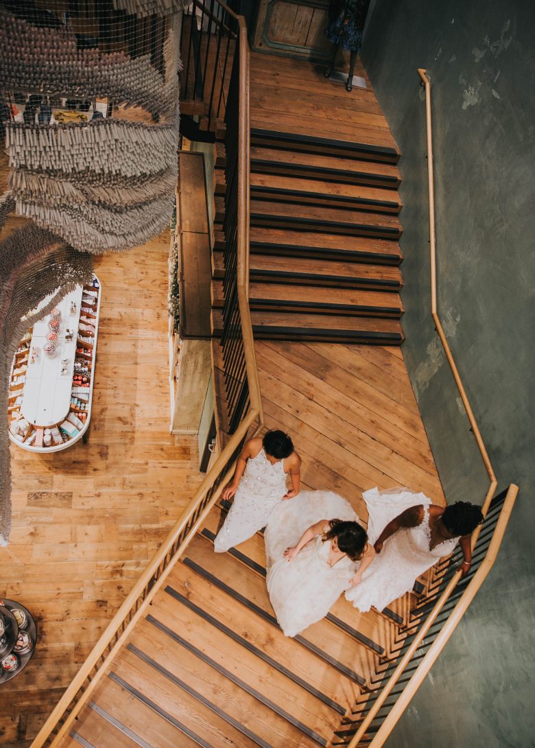 three brides walking down the stairs wearing BHLDN dresses at the Anthropologie palo alto store