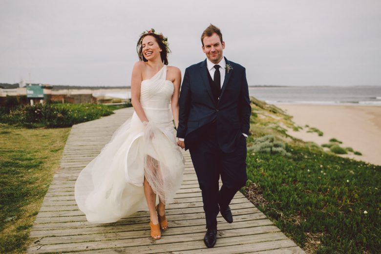 bride and groom walking on a path near the ocean