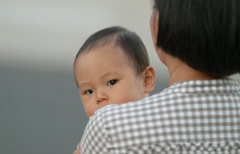 a baby looking over a woman's shoulder