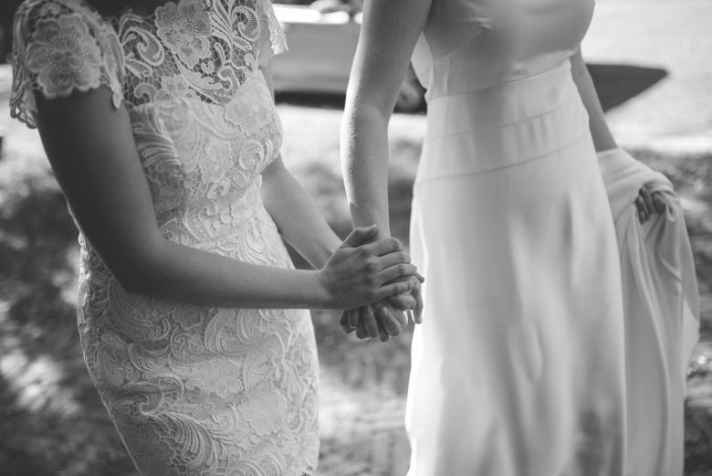 a black and white photo of women holding hands
