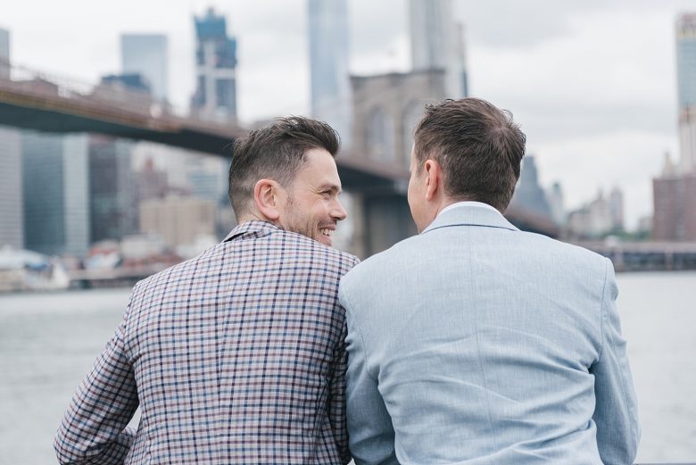 portrait of two grooms from behind, looking at Brooklyn Bridge and Manhattan skyline