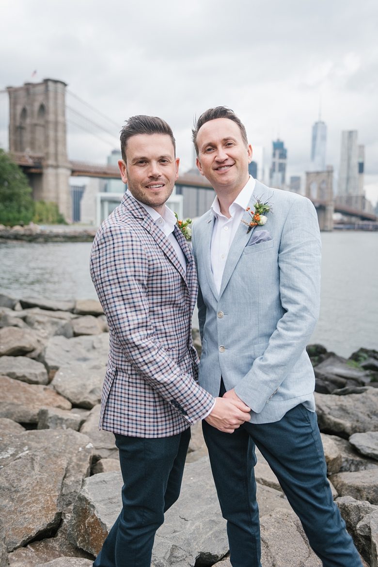 portrait of two grooms in front of Brooklyn Bridge and Manhattan skyline