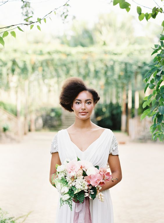 holding her pastel flower bouquet - a bride looks confidently at the camera