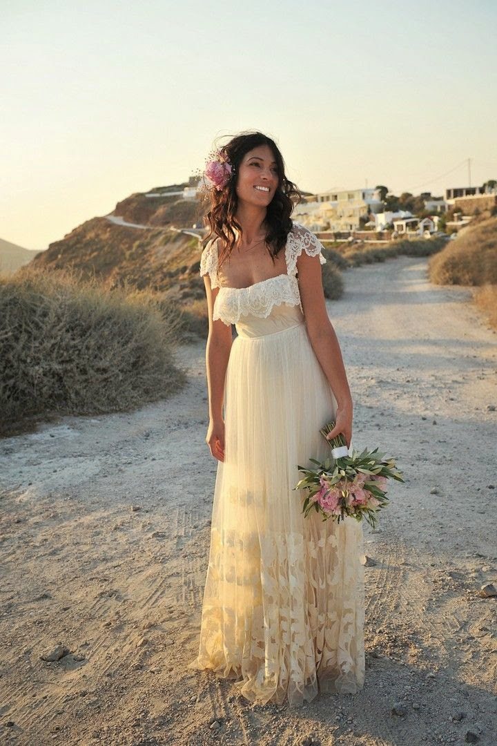 a bride stands in the middle of a dirt road in the mountains with the setting sun bathing her in beautiful orange light