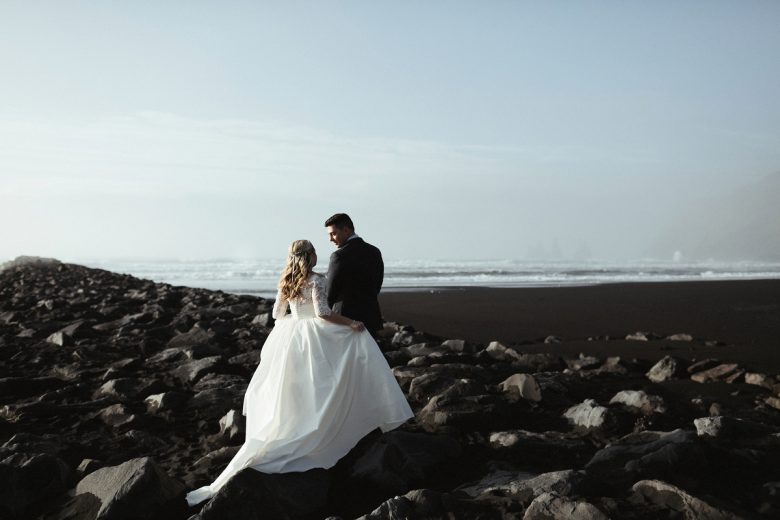 Bride and groom on rocks near ocean