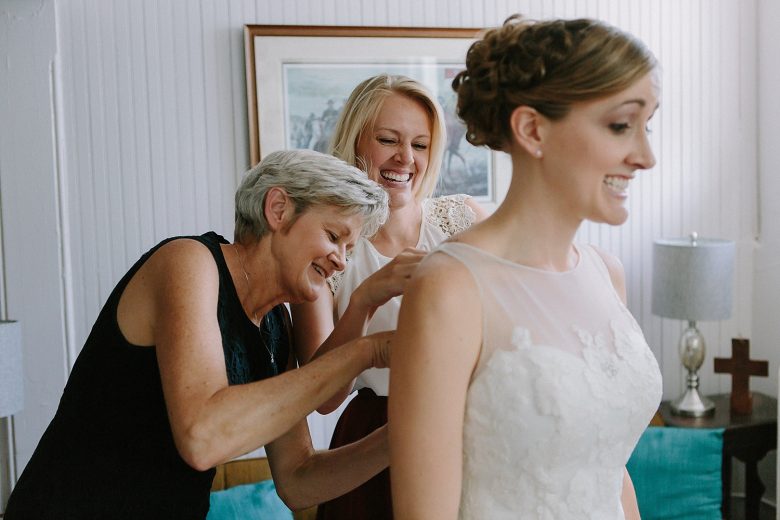 Bride getting buttoned into dress