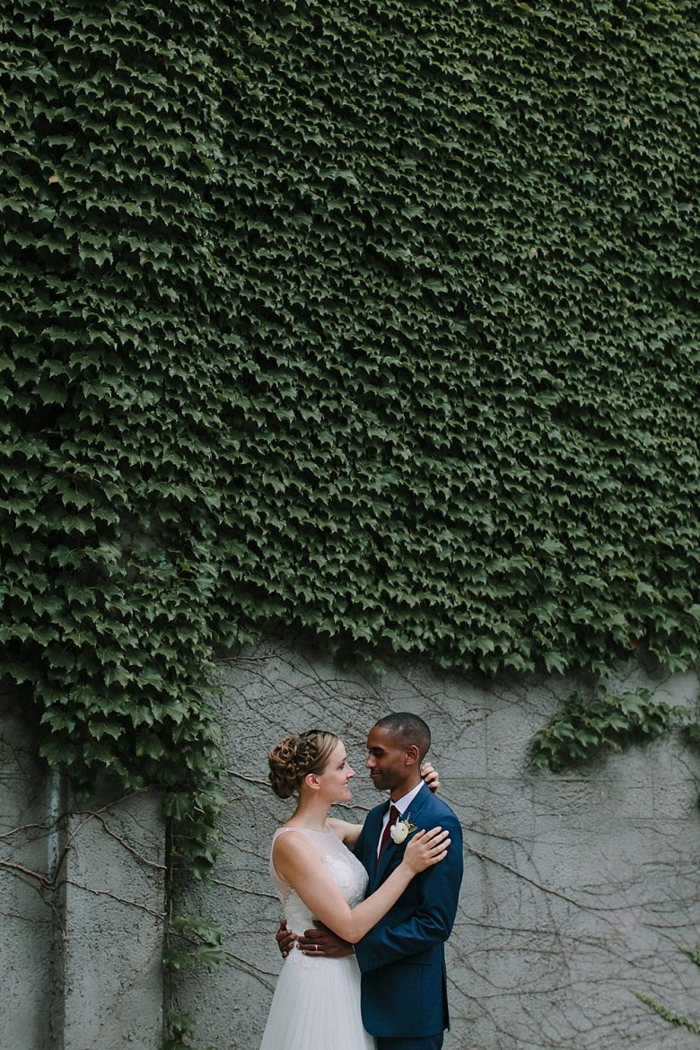Bride and groom portrait in front of ivy-covered wall
