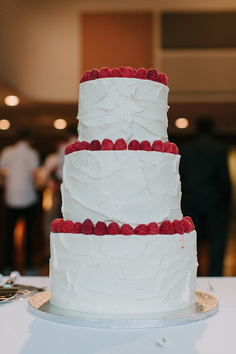 Three-tiered white wedding cake with raspberries