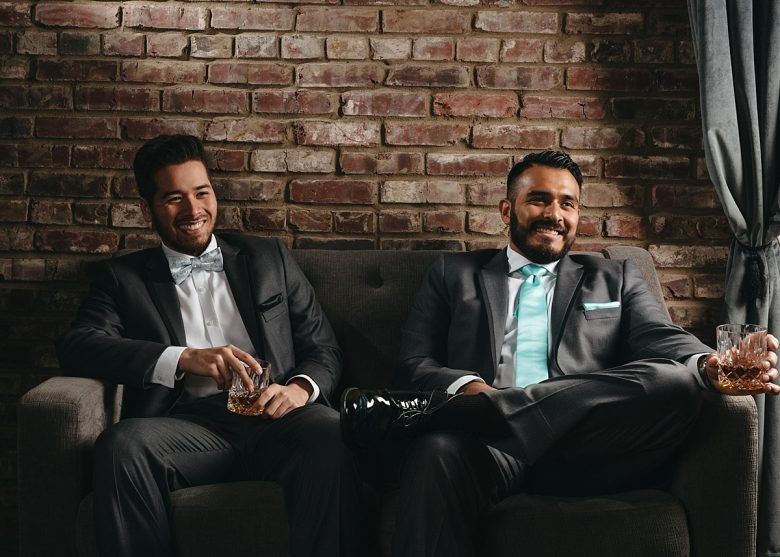 men in gentux suits sitting on a couch with drinks