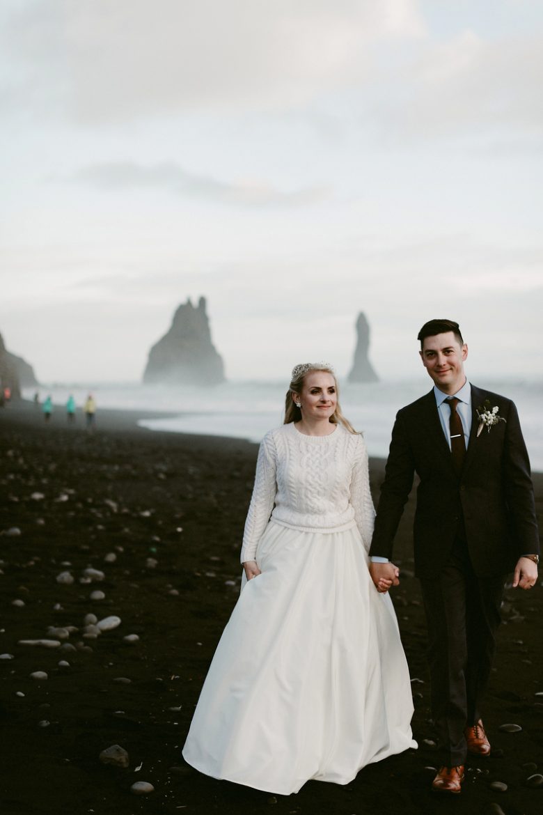 Bride wearing white cable-knit sweater, with groom in Fjaðrárgljúfur
