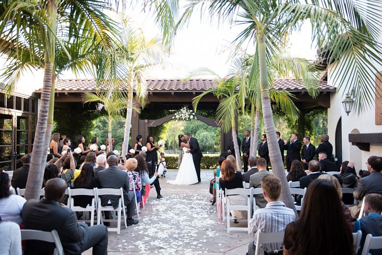 Bride and groom kissing at wedding ceremony in tropical courtyard